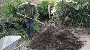 Joe turning a compost pile with a pitch fork